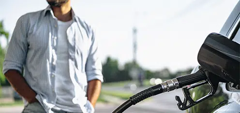 Joven en gasolinera, llenando tanque de carro negro